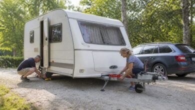 Paar richtet einen Wohnwagen mit Wasserwaage und Unterlegkeilen aus