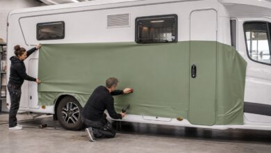 Zwei Fachleute folieren eine Seitenfläche des Wohnmobils