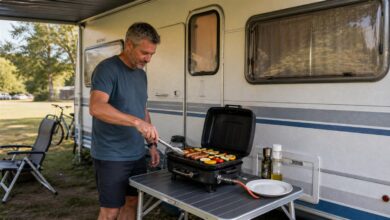 Camper grillt sicher auf einem kompakten Gasgrill neben dem Wohnwagen