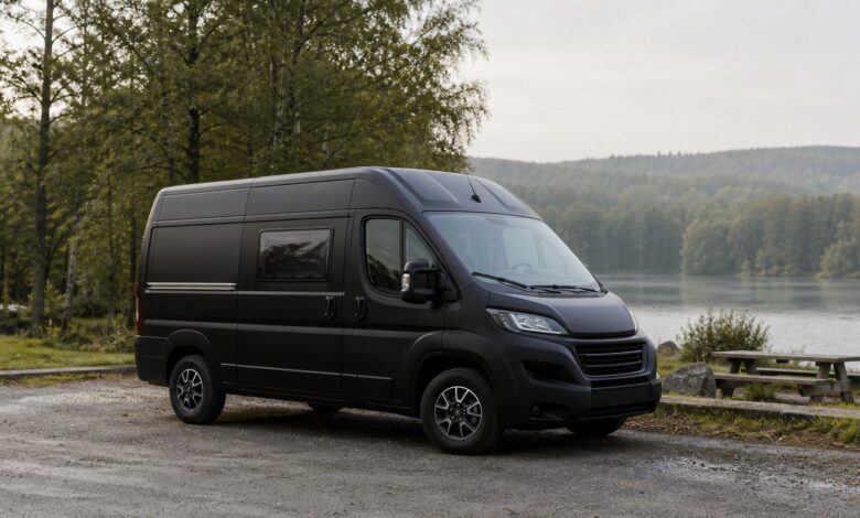 Kompakter schwarzer Hymer Sydney Campingbus an einem See