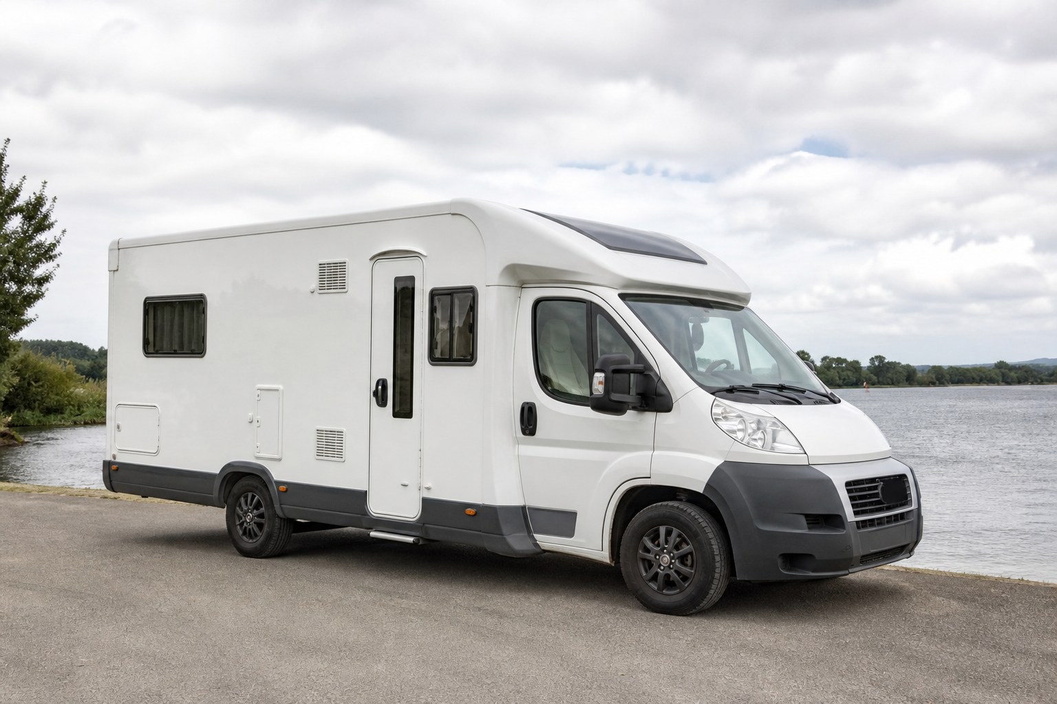 Weißes Pilote P696D Sensation Wohnmobil an einem See