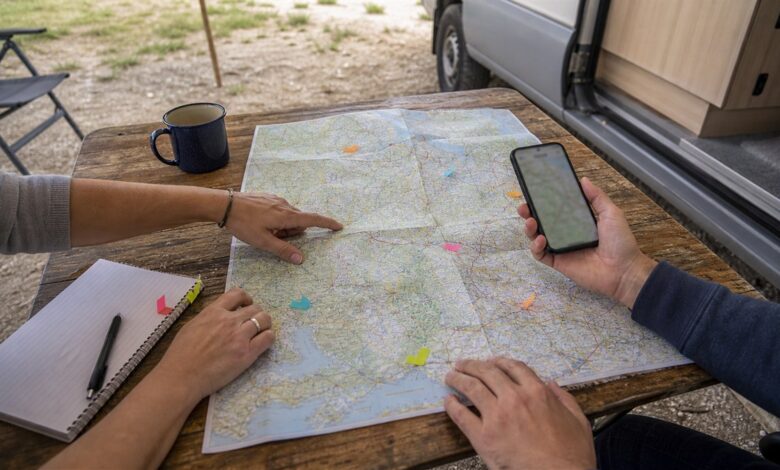 Zwei Camper planen ihre Route mit Karte und Smartphone