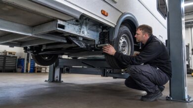 Werkstatttechniker prüft Fahrwerk und Achse eines Wohnwagens