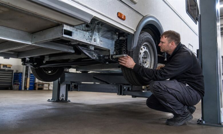 Werkstatttechniker prüft Fahrwerk und Achse eines Wohnwagens