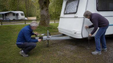 Älteres Paar nivelliert gemeinsam einen Wohnwagen auf dem Campingplatz