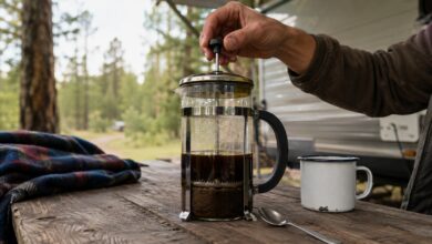 French Press wird auf einem Campingtisch von Hand heruntergedrückt