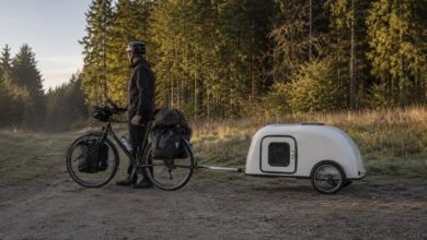 Tourenrad mit kompaktem Fahrradwohnwagen am Rand eines Waldweges