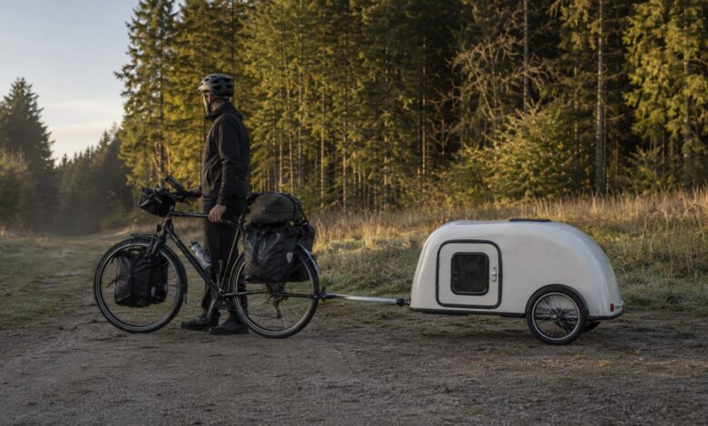 Tourenrad mit kompaktem Fahrradwohnwagen am Rand eines Waldweges