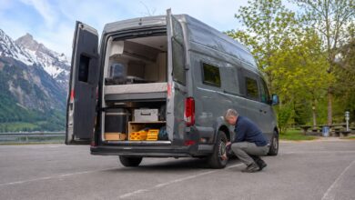 Grauer Campervan beim Reifencheck nach einer langen Reise