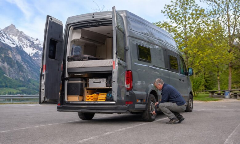 Grauer Campervan beim Reifencheck nach einer langen Reise
