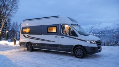 Weiß-grauer winterfester Campervan auf einem verschneiten Stellplatz
