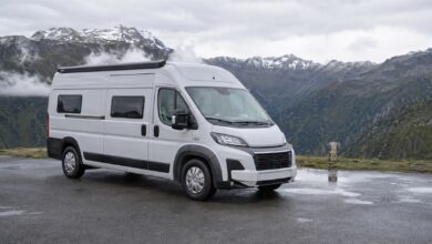 Weißer Hochdach-Campervan auf einem nassen Alpenparkplatz