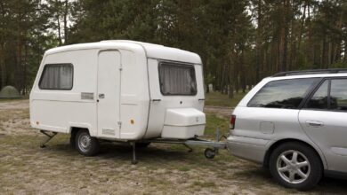 Kleiner einachsiger GFK-Wohnwagen an einem Zugfahrzeug auf einem Waldcampingplatz
