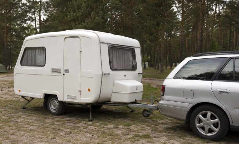 Kleiner einachsiger GFK-Wohnwagen an einem Zugfahrzeug auf einem Waldcampingplatz